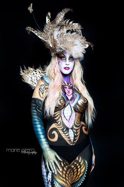 Model in a feathered headdress with black and gold body design