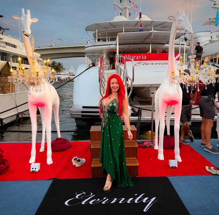 Madelyn Greco in a green gown on a red carpet at a marina