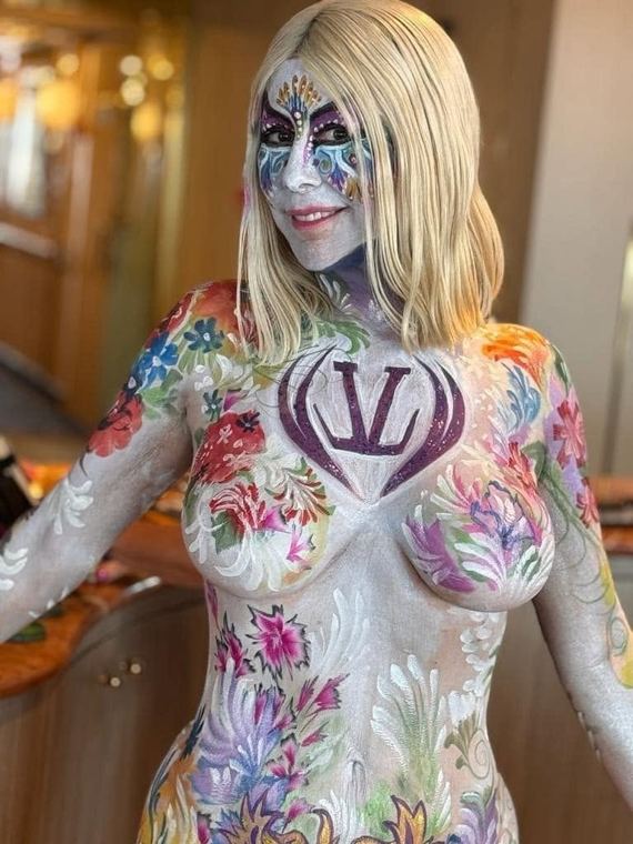 Model painted with a sponsor logo among white and pink flowers