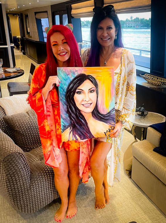 Madelyn Greco and a guest holding the guest’s painted portrait