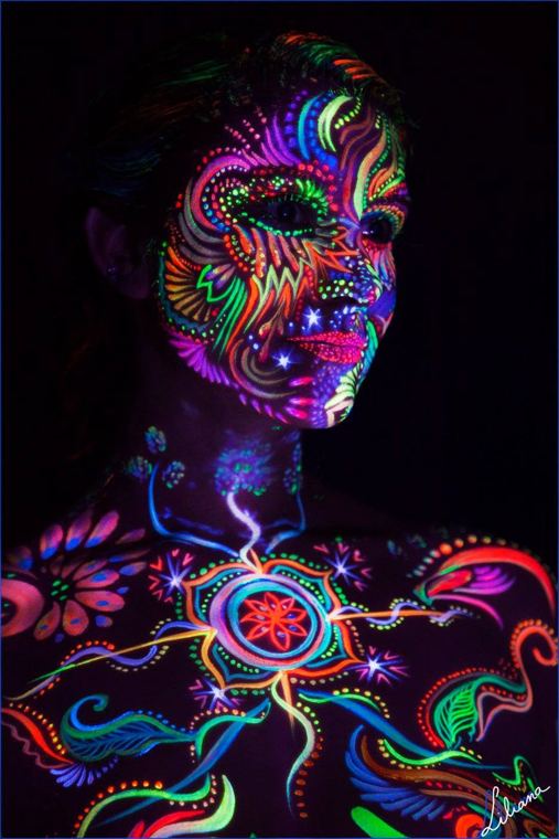 Face and chest glowing in fluorescent paint under UV light