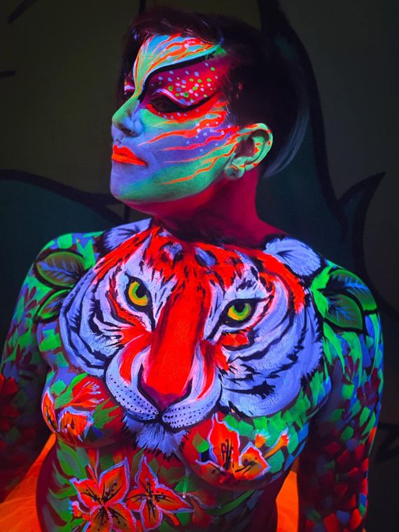 Tiger face painted on a chest, glowing under UV light