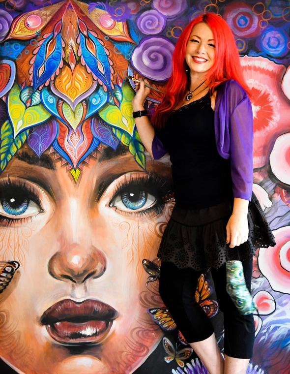Madelyn Greco beside a mural of a woman’s face