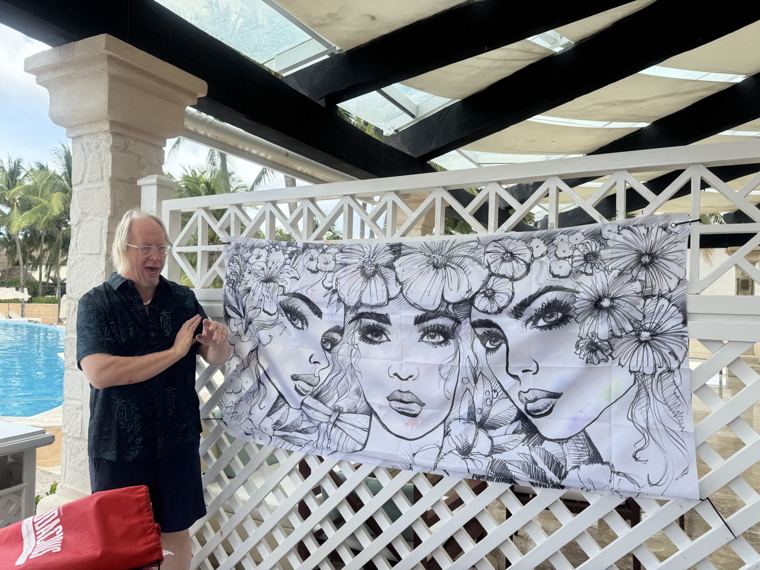 Scott Fray beside a banner of three faces, drawn in black and white